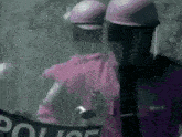 two police officers wearing pink helmets are holding a sign that says police .