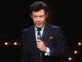 a man in a suit and tie is holding a microphone in his hand