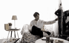 a man in a white sweater is sitting on a couch with his arms outstretched .