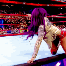 a woman with purple hair is wrestling in a ring with a crowd watching