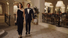 a man and woman are walking down a hallway holding hands