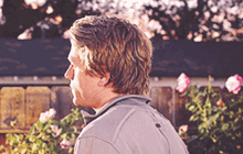 a man standing in front of a fence with flowers