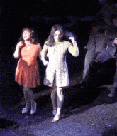 a woman in an orange dress is standing next to another woman