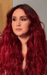 a woman with very long red hair is looking at the camera