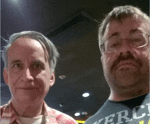 two men are posing for a picture with one wearing a shirt that says mercy