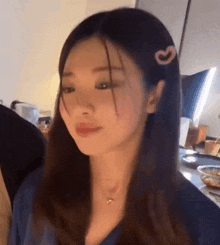 a woman with long hair and a heart shaped hair clip is sitting at a table .