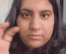 a close up of a woman 's face with her finger on her nose .