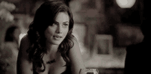 a woman is sitting at a table with a glass of wine in her hand .