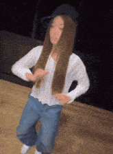 a woman with long brown hair wearing a white shirt and blue jeans