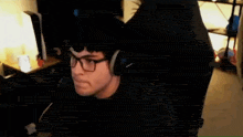 a man wearing glasses and headphones is sitting in a chair and talking on a cell phone .