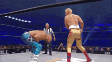 two men are wrestling in a ring with a referee standing behind them .