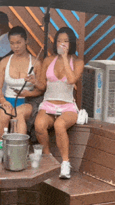 a woman in a pink top and shorts sits on a bench next to an air conditioner that says ' cooler air '