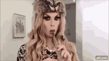 a drag queen is eating a chocolate bar with a spoon .