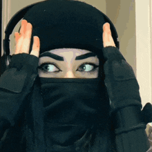 a woman wearing a black beanie and a black mask