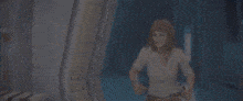 a woman in a white shirt is standing in a room with a blue background .