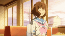 a girl in a sailor uniform sits at a table with a drink