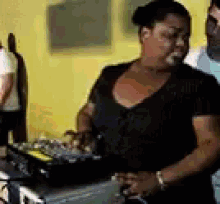 a woman in a black shirt is standing in front of a dj controller .