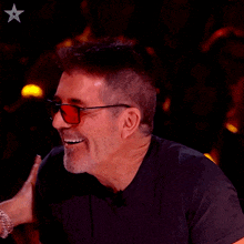 a man wearing sunglasses and a black shirt has a star on his chest