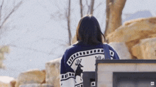 a woman wearing a blue and white sweater with a deer on it is standing in front of a computer monitor .