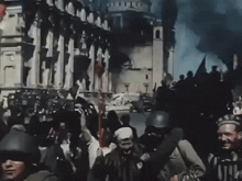 a group of people standing in front of a burning building with smoke coming out of it