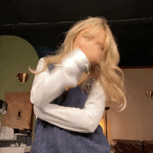 a woman in a blue dress and white shirt is dancing in a room