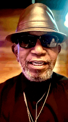 a man wearing sunglasses and a hat is smiling for the camera