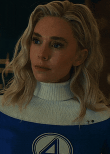 a woman wearing a white turtleneck and a blue superhero costume with the letter 4 on it