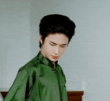 a man in a green shirt with a pattern on it looks down