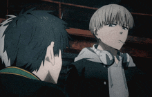 a man with headphones on his neck looks at another man