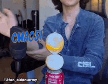 a man in a denim shirt is holding a can of coke in his hands
