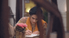 a woman is writing in a notebook at a table .