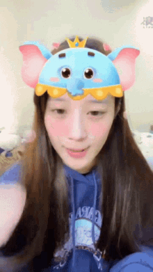 a woman wearing a blue hoodie and a blue elephant mask on her head