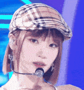 a close up of a woman wearing a plaid hat and a microphone