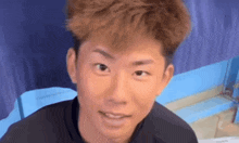 a close up of a man 's face with a blue curtain in the background