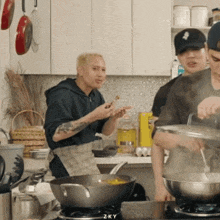 a group of men are cooking in a kitchen and one of them is wearing a black hat with the letter k on it