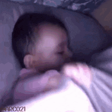a blurry picture of a baby sleeping with the watermark arco21 on the bottom