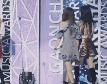 two women are standing in front of a sign that says music awards .