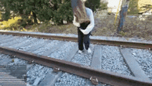 a woman is standing on train tracks with her head down