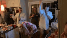 a group of people are dancing in a kitchen with a man wearing a shirt that says ' daddy ' on it