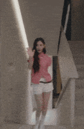 a woman in a pink plaid shirt and white shorts is standing in front of a mirror
