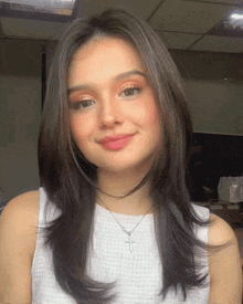 a woman wearing a white tank top and a cross necklace