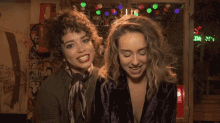two women standing next to each other with a fire extinguisher in the background