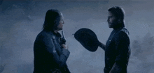a man is putting a cowboy hat on another man 's head in a dark room .