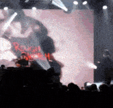 a man playing drums in front of a large screen that says rough rider on it
