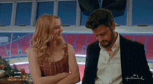 a man and a woman are standing in front of a hallmark ad