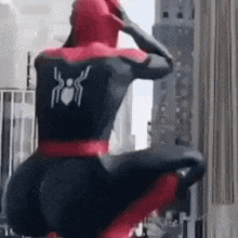 a man in a spiderman costume is squatting down in front of a city .