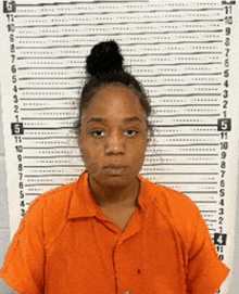 a woman in a orange shirt is standing in front of a height chart .