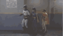 batman and batgirl are standing next to each other in front of a sign that says keep door locked at all times