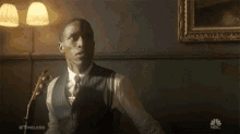 a man in a suit and tie is holding a guitar in front of a nbc ad