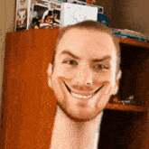 a man with a beard is making a funny face in front of a shelf .